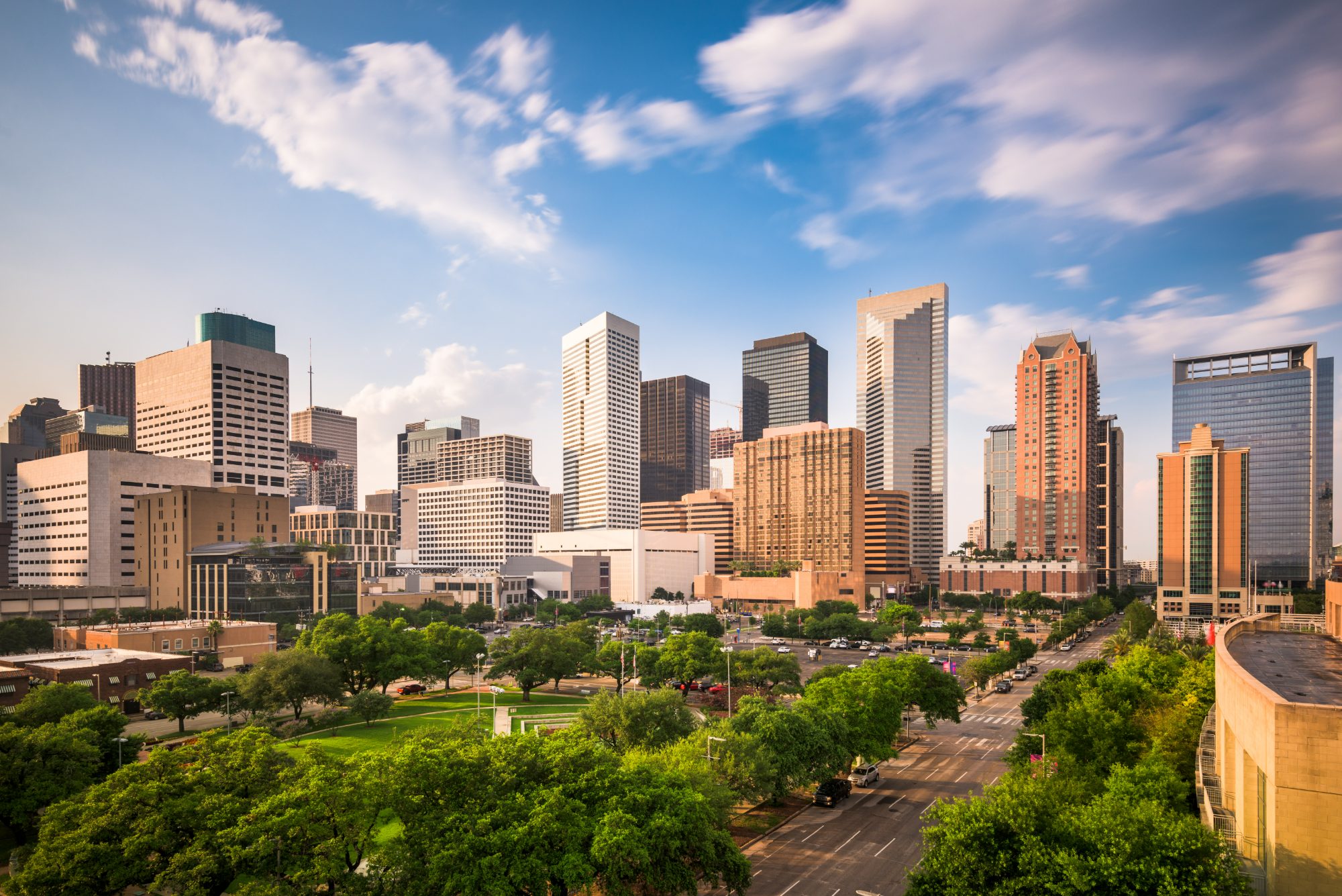 Houston skyline with downtown skyscrapers, green park, and blue sky with clouds