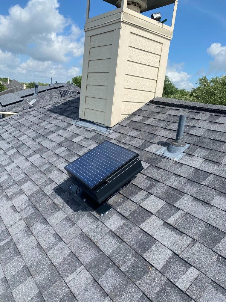 Solar powered roof ventilator installed on residential asphalt shingle roof with white equipment structure