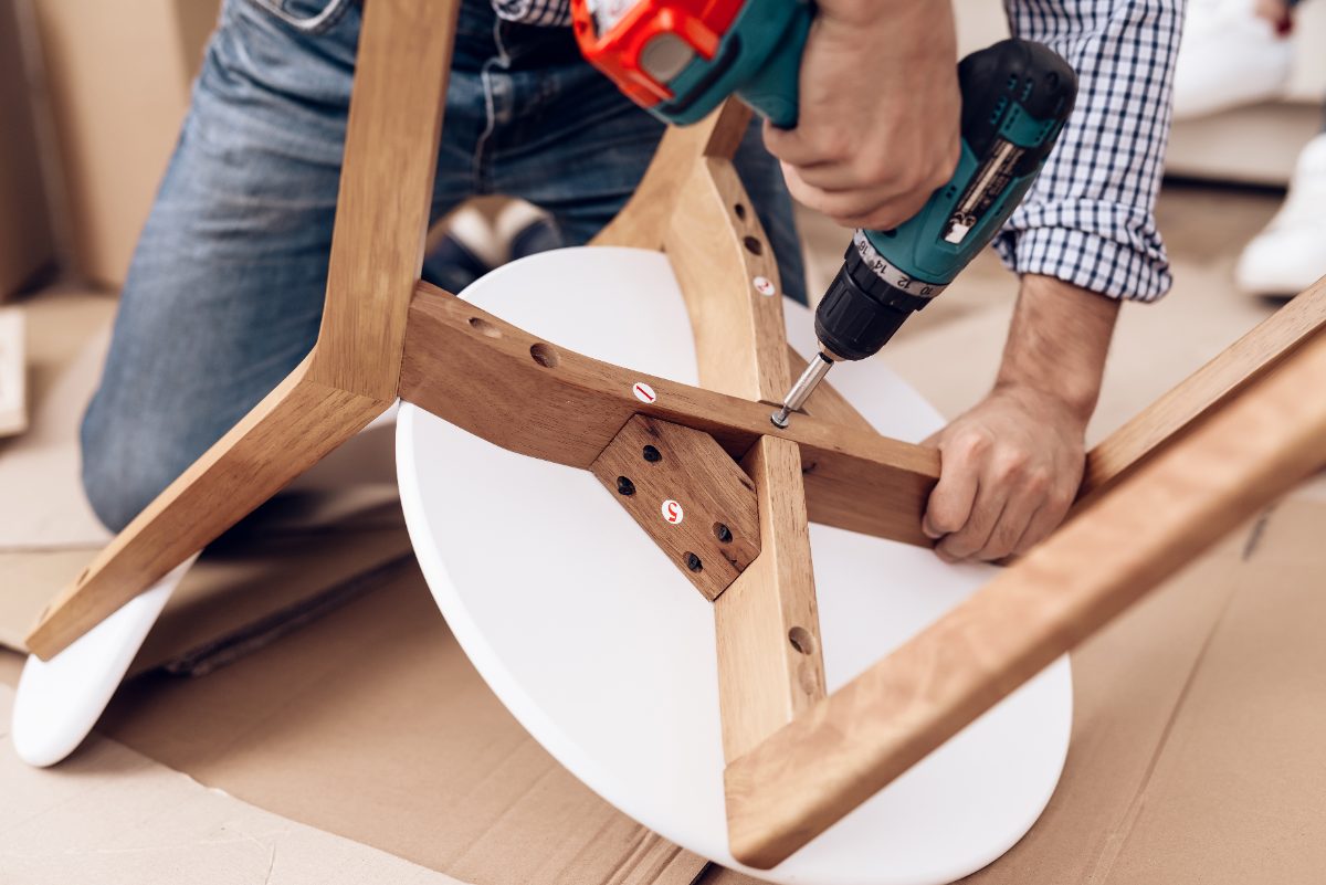 Group assembling wooden chair with cordless drill and white seat cushion
